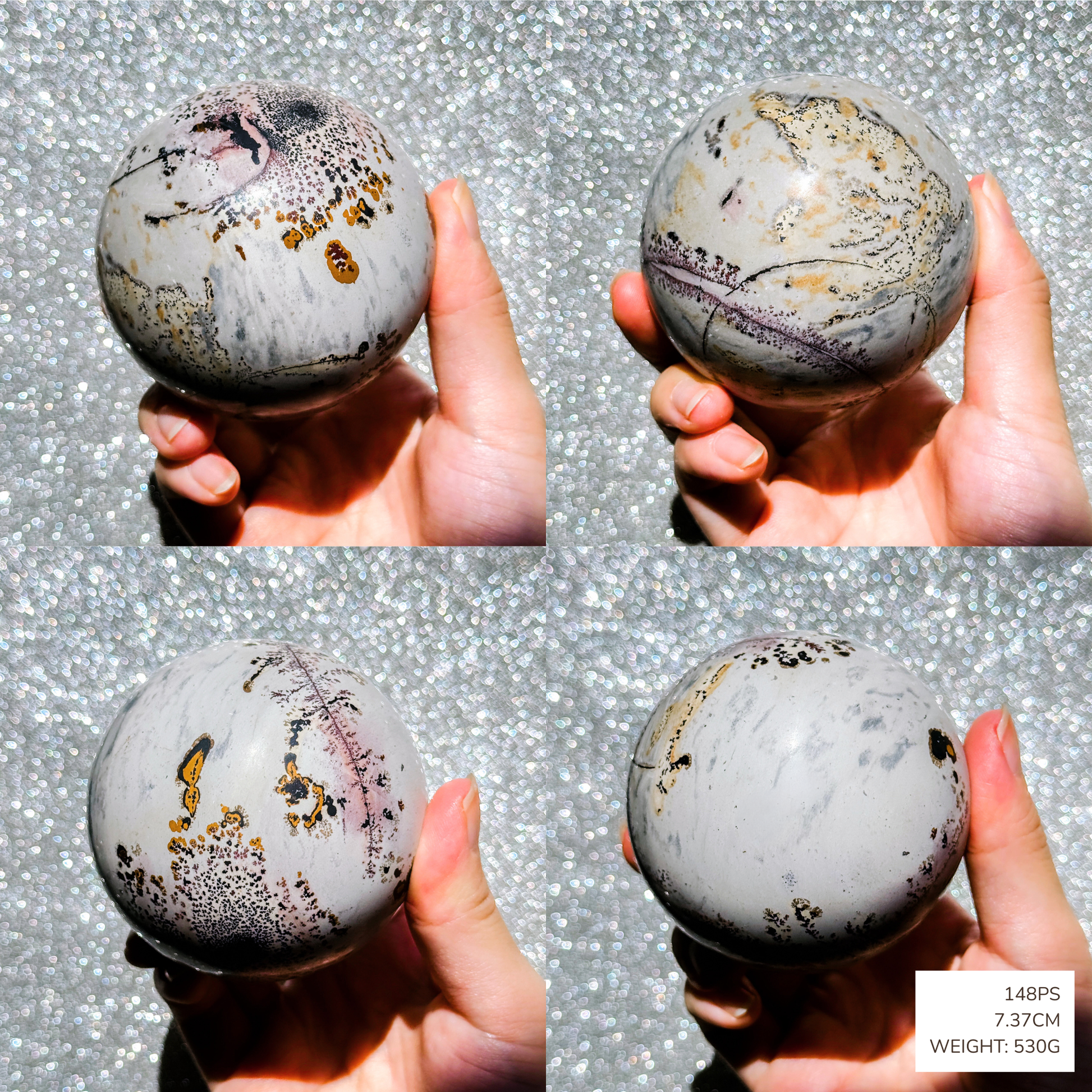 Marble-like picture jasper sphere held by a hand against a textured gray background