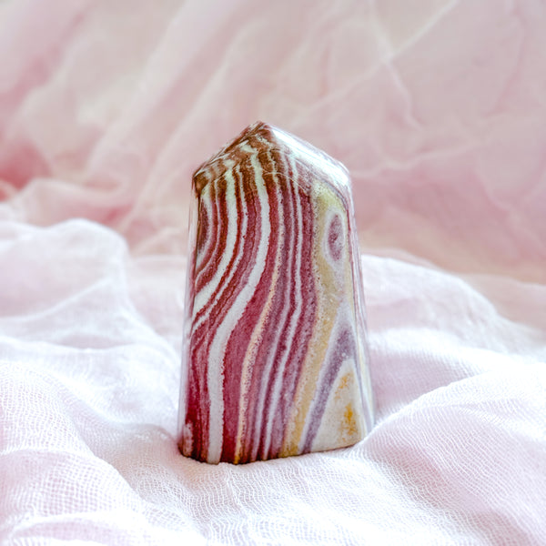 Multicolored striped jasper crystal on a soft pink fabric background